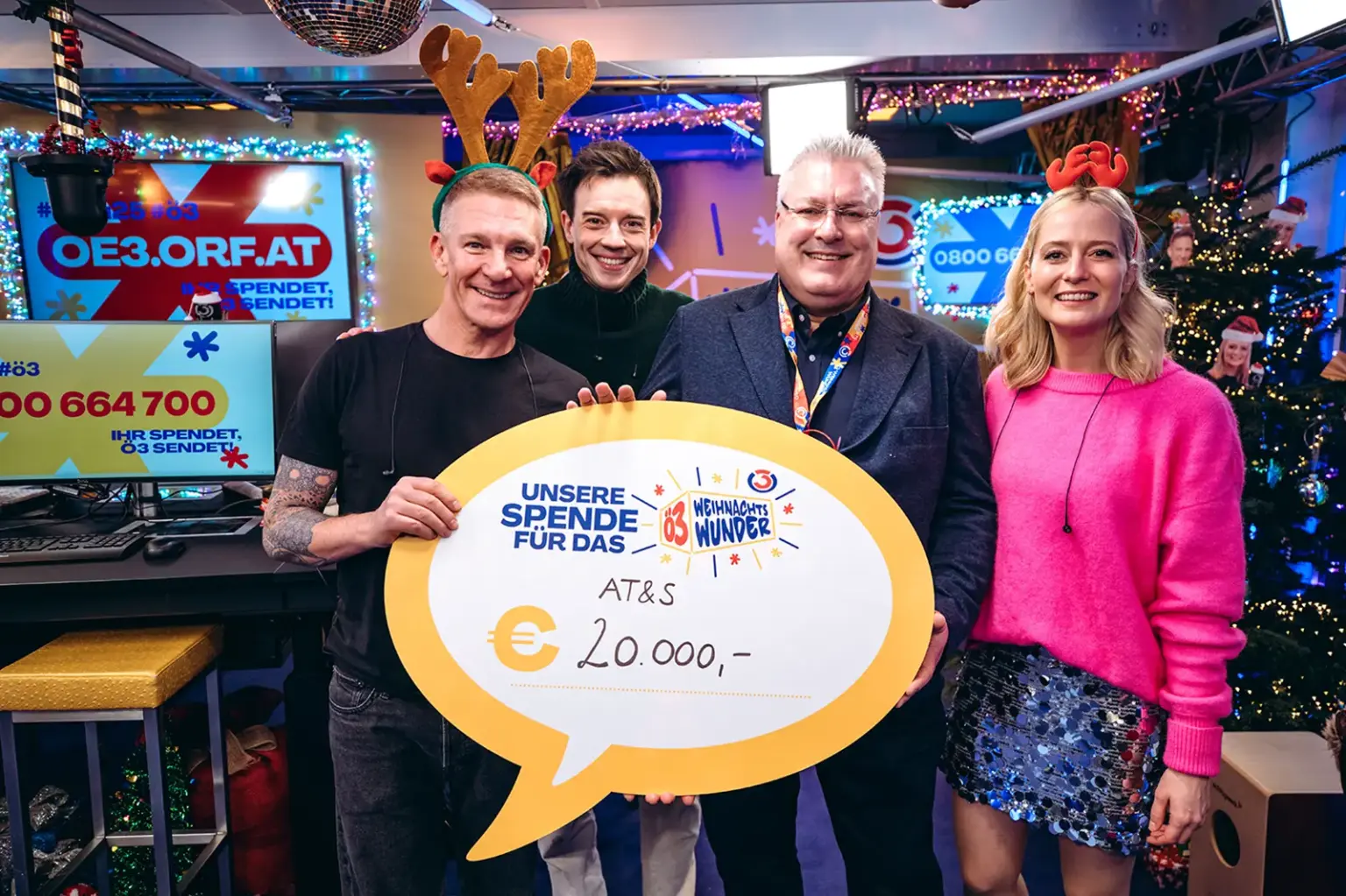 Drei Männer und eine Frau in weihnachtlicher Kostümierung bei einer Spendenübergabe