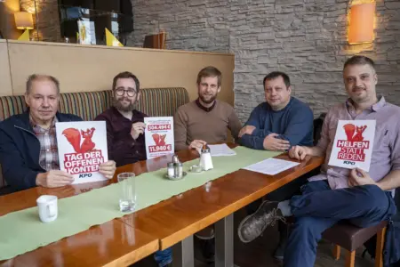 KPÖ lud zum Tag der offenen Konten Fünf Männer sitzen an einem Tisch, drei davon halten einen Zettel hoch.