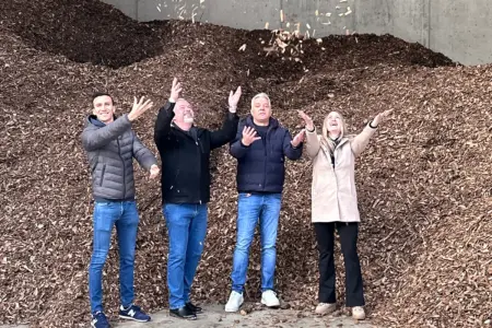 Drei Männer und eine Frau werfen Hackschnitzel in die Luft