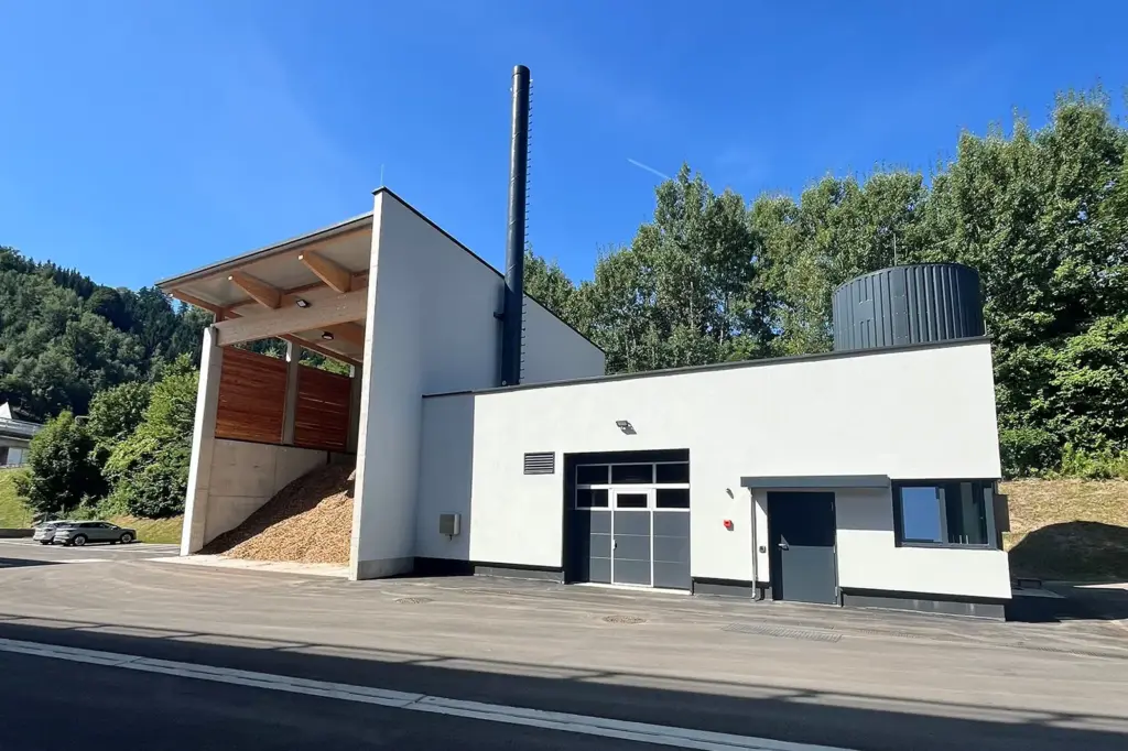 Ein Haus mit Hackschnitzelschütte und hohem Schlot