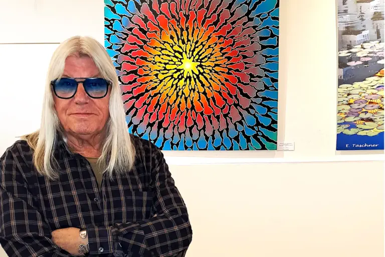 Ein Mann mit langen weißen Haaren vor einem abstrakten Ölgemälde