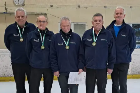 Fünf Männer stehen in einer Eishalle und haben Medaillen umgehängt.