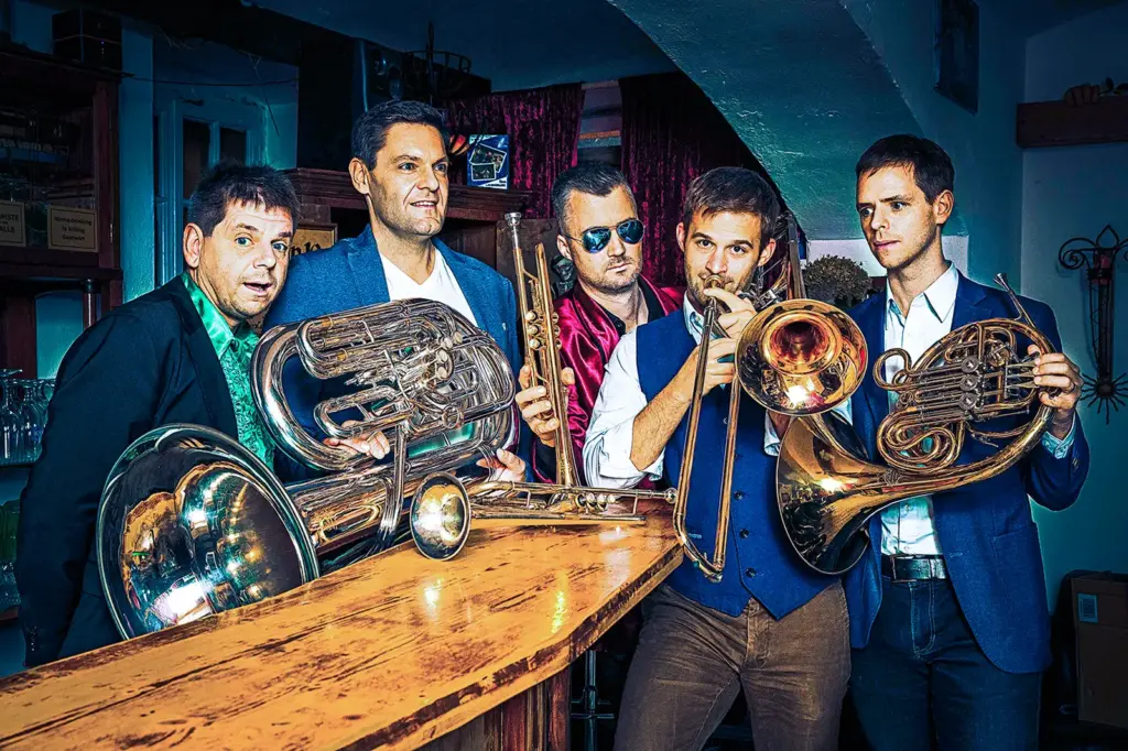 Fünf Männer mit Blechblasintrumenten an einer Bar