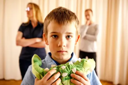 Stärkung für Kinder bei Trennung und Scheidung Ein Kind mit Plüschtier, im Hintergrund voneiander abgewandt eine Frau und ein Mann
