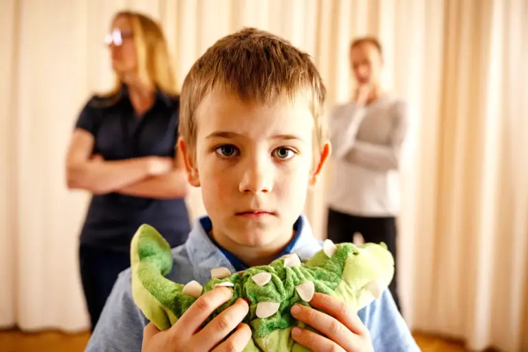 Stärkung für Kinder bei Trennung und Scheidung Ein Kind mit Plüschtier, im Hintergrund voneiander abgewandt eine Frau und ein Mann