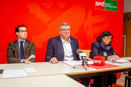 Die Roten teilen kräftig aus Zwei Männer und eine Frau sitzen mit ernsten Mienen an einem Tisch, vor ihnen ein Mikrofon