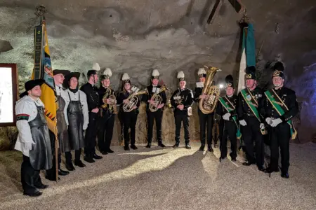 Zwölf Menschen in traditioneller Bergmannstracht und Musikinstrumenten in einem Bergwerk