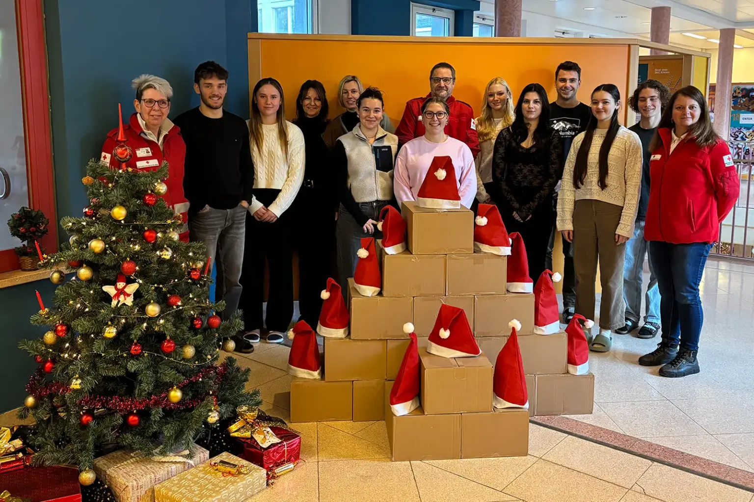 Eine Gruppe Schülerinnen und Schüler vor einem Paketstapel neben einem Christbaum