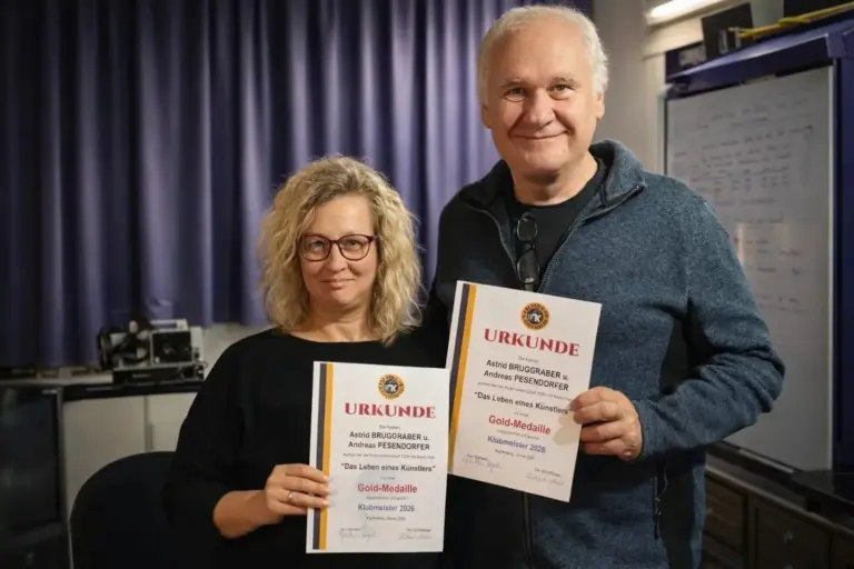 Vom Filmklub vergoldet Eine Frau und ein Mann stehen lächelnd nebeneinander und halten Urkunden in Händen.