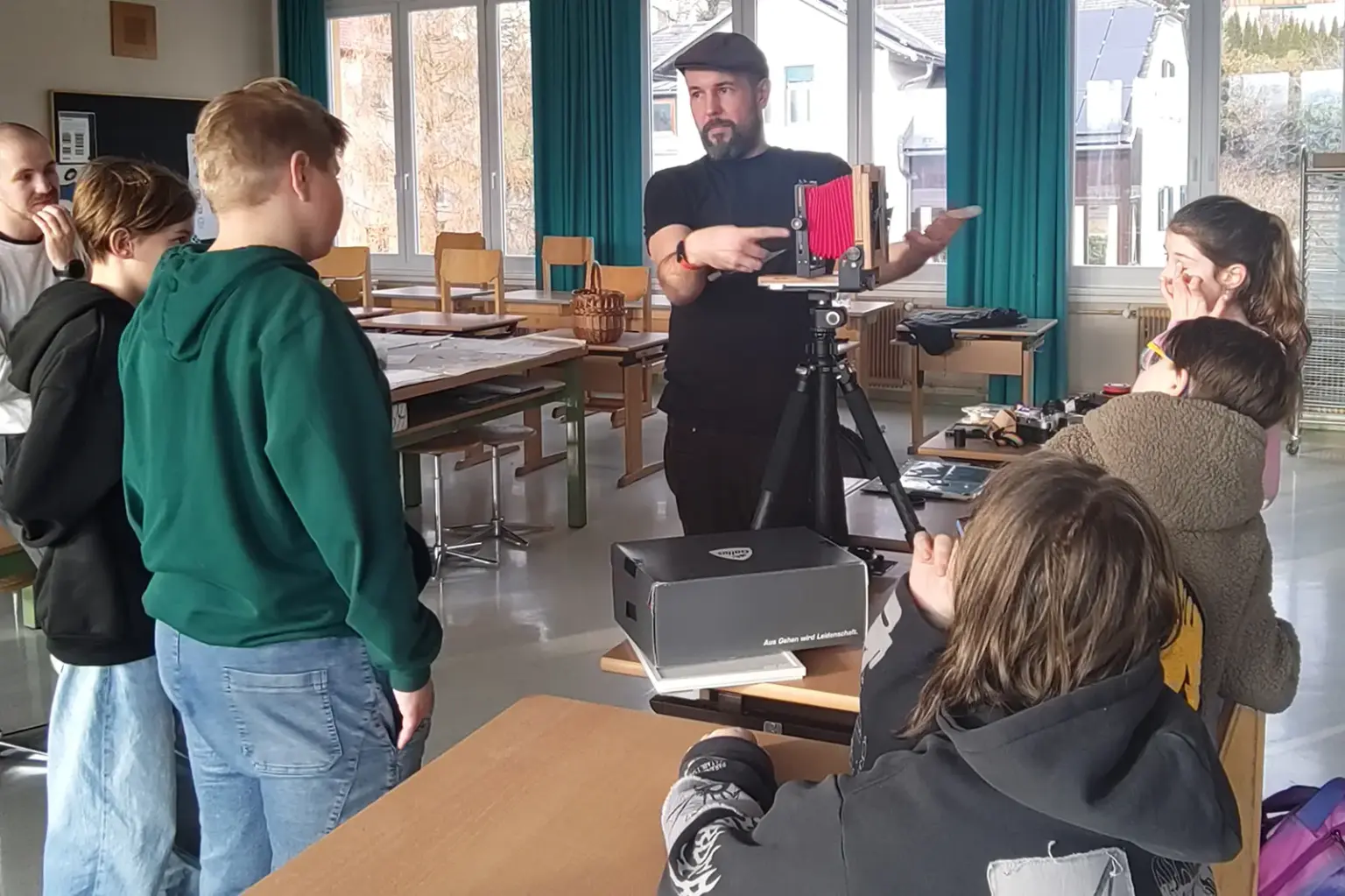 Ein Mann erklärt Schülern eine alte Fotokamera