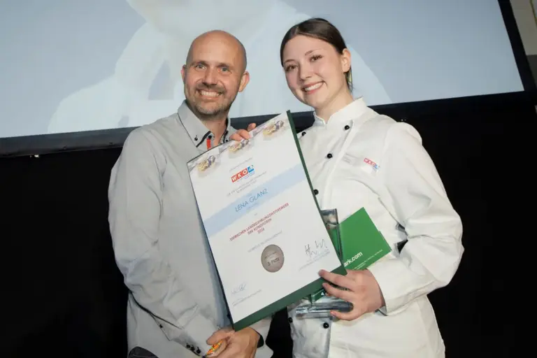 Ein Mächen und ein Mann präsentieren einen Preis und eine Urkunde