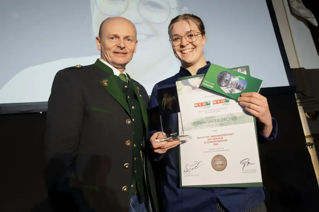 Ein Mädchen und ein Mann präsentieren einen Preis und eine Urkunde