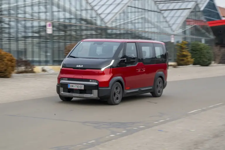 Ein rot-schwarzer Kleinbus fährt auf einer Straße von rechts nach links