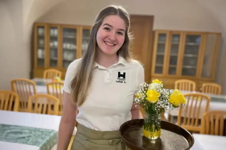 „Wir sammeln viel Praxiserfahrung“ Eine junge Frau mit einem Tablett in der Hand.