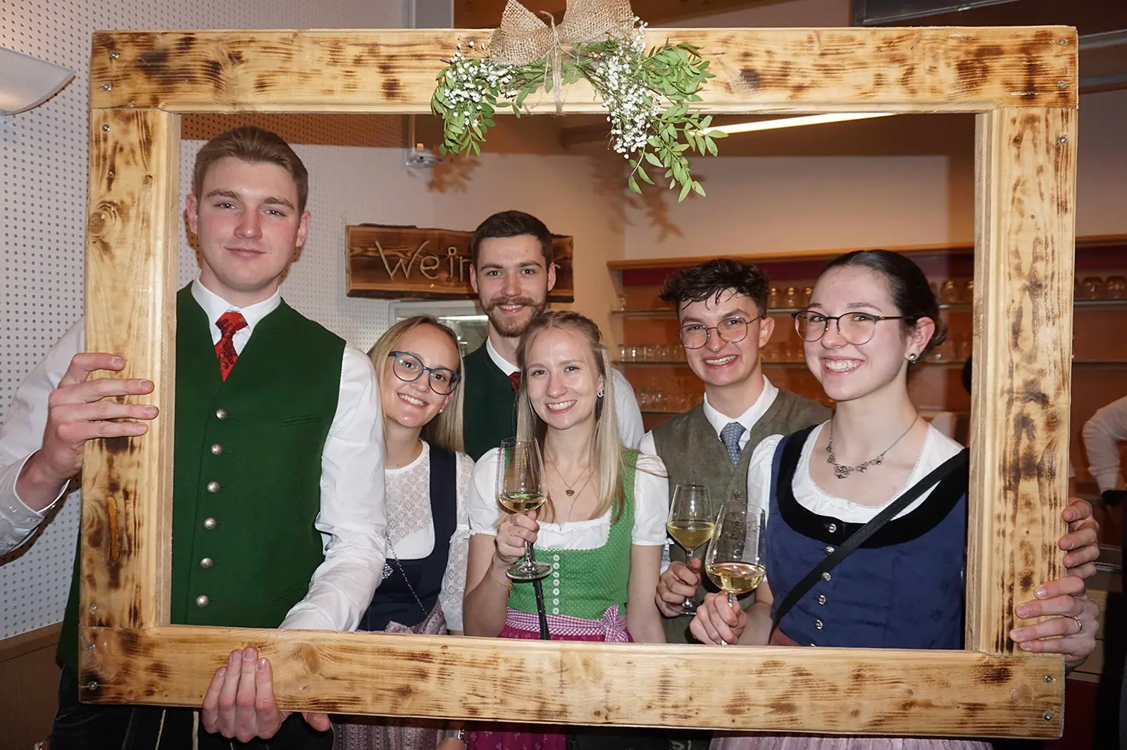 Junge Menschen in Tracht blicken durch einen Bilderrahmen