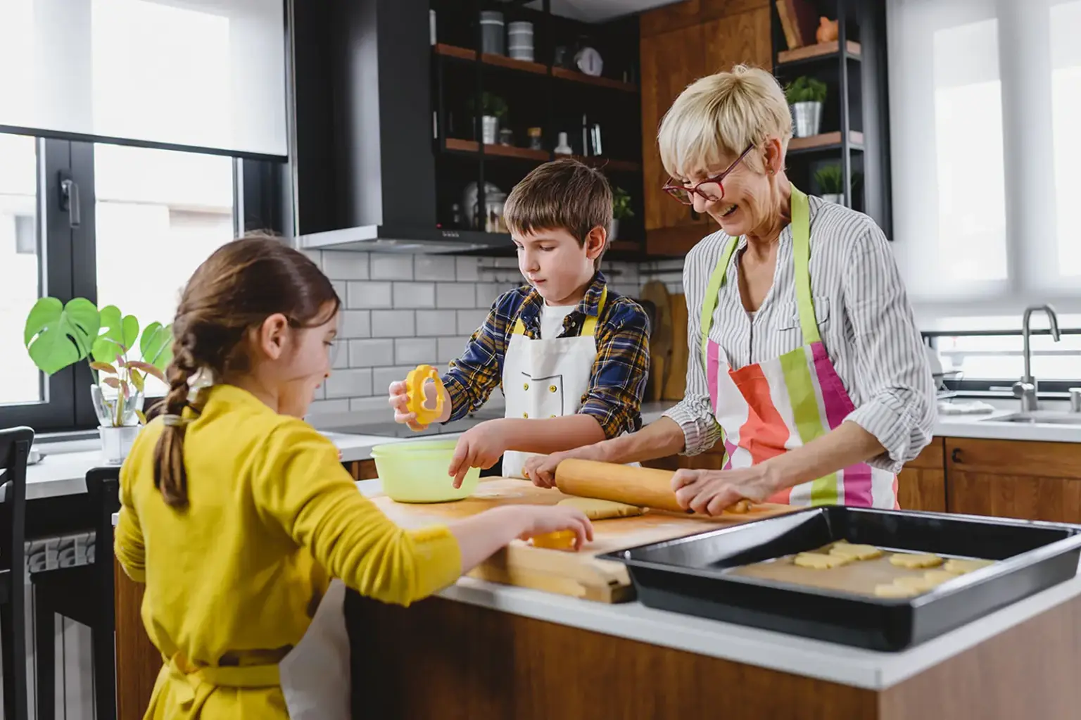 Eine ältere Frau mit zwei Kindern in der Küche beim Backen