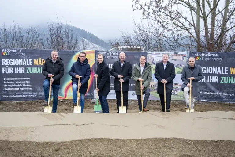 Sieben Männer vor einem Erdhaufen mit jeweils einem Spaten in der Hand.