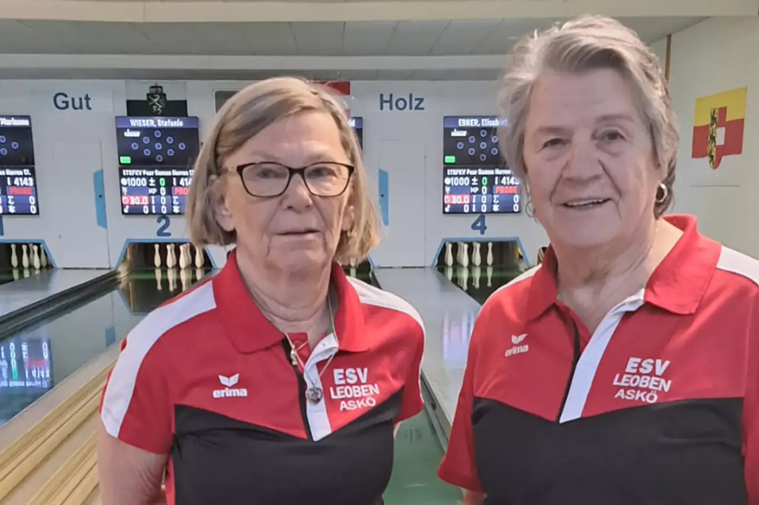 Zwei Frauen im Vordergrund und eine Kegelbahn im Hintergrund.