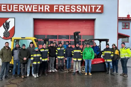 Ein Gruppe von Personen vor zwei Gabelstaplern
