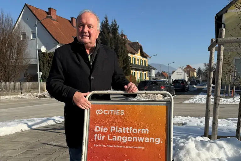 Ein Mann mit schütterem Haar präsentiert ein Plakat