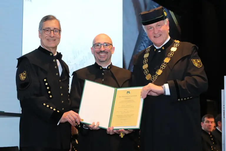 Drei Männer halten eine Urkunde