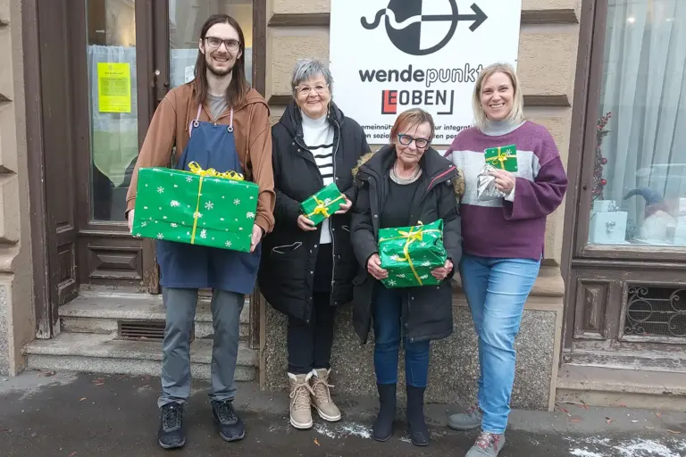 Vier Personen mit Geschenkspaketen vor einem Haus