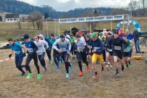 Zwei Drittel sind gelaufen Zahlreiche Läufer mit Startnummer, dahinter ist eine Start- und Zielbogen zu erkennen.