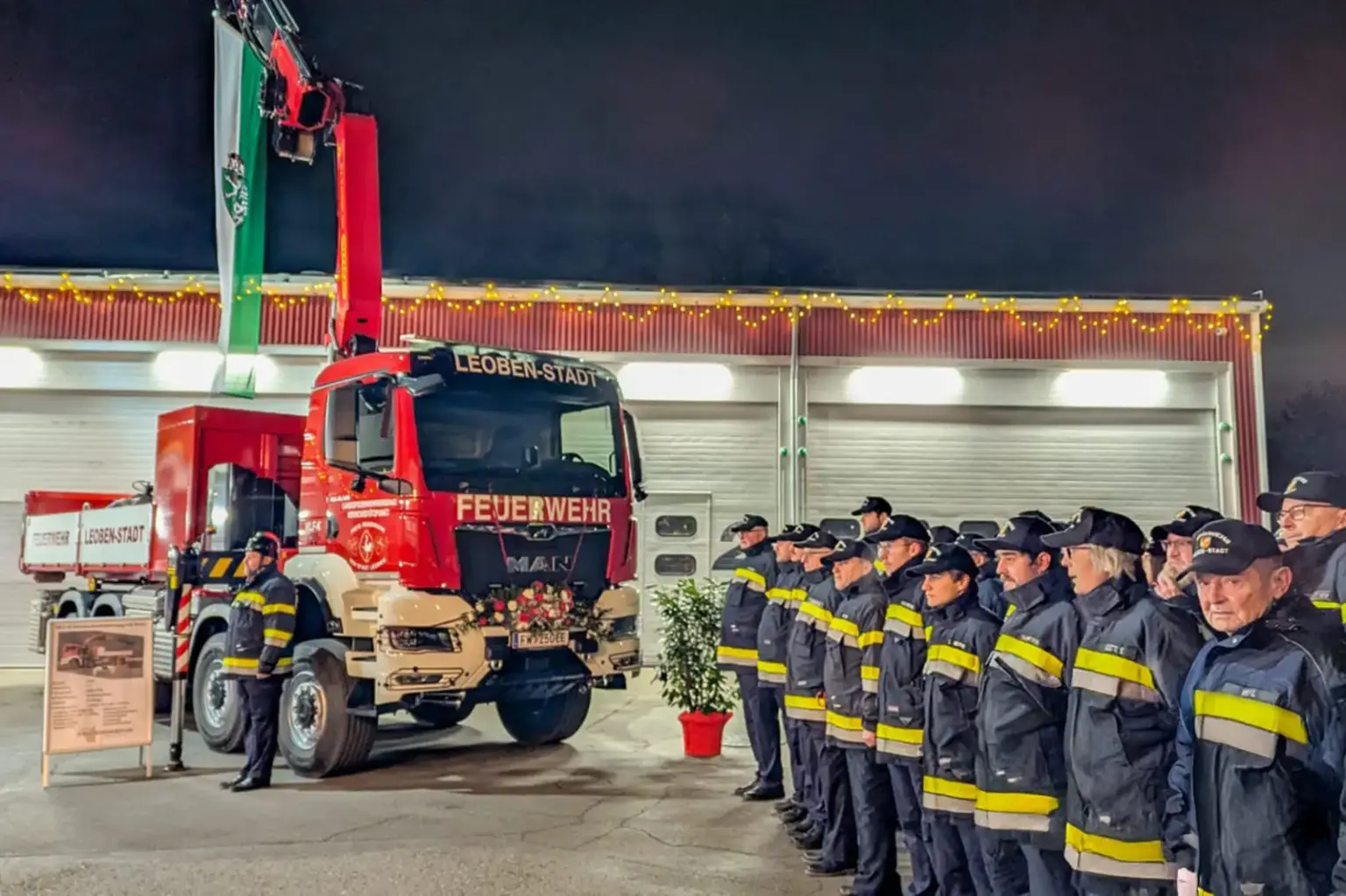 Eine Gruppe Feuerwehrmänner vor einem Einsatzfahrzeug mit Kran