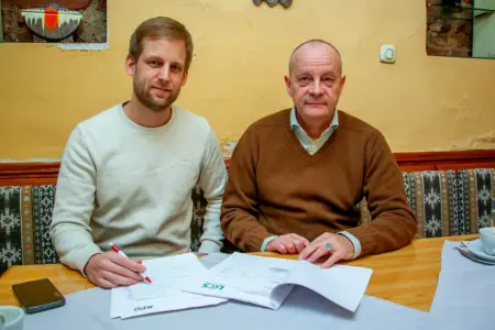 Zwei Männer sitzen an einem Tisch und blättern in Unterlagen