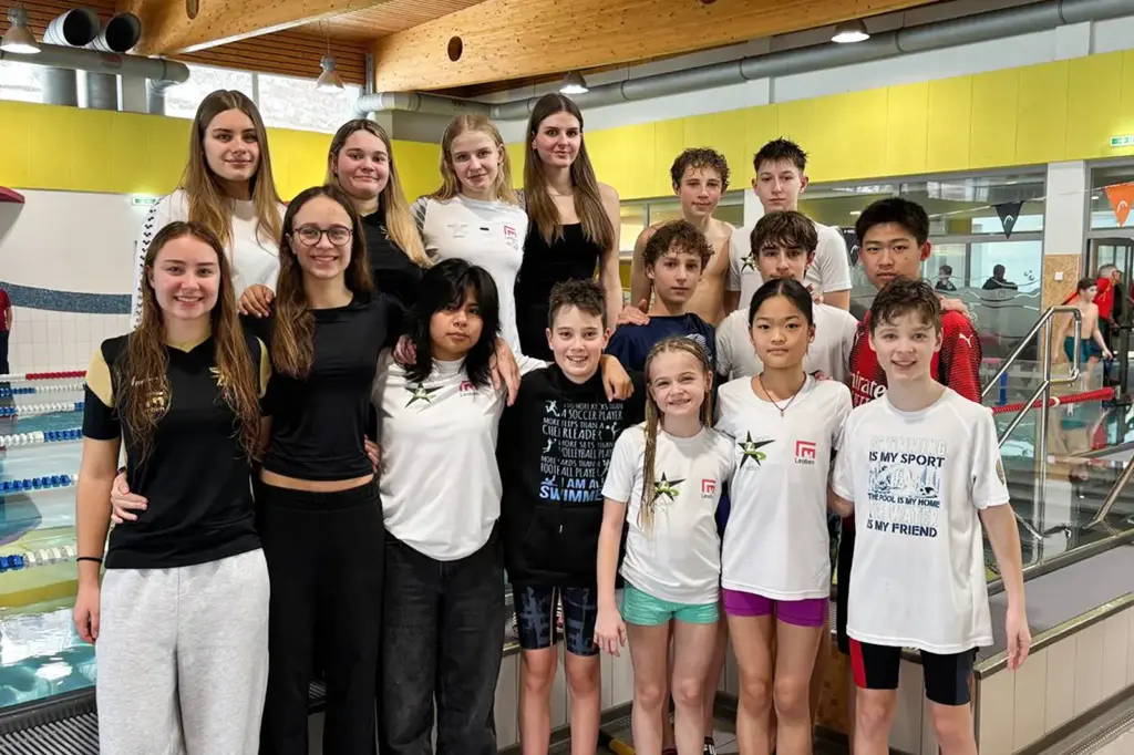 Eine Gruppe junger Menschen beim Gruppenfoto in einem Schwimmbad.