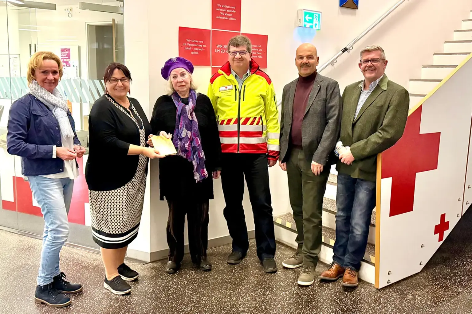 Drei Frauen und drei Männer stehen vor einem Treppenaufgang