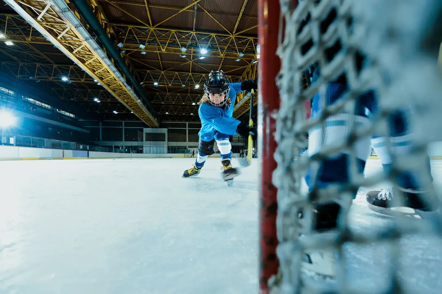 Ein Kind in Eishockeyausrüstung fährt auf ein Tor zu.