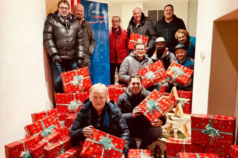 Elf Männer mit zahlreichen in rotes Papier gehüllten Geschenkkartons