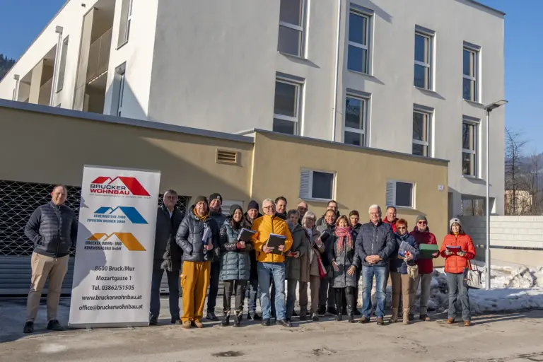 Rund 20 Menschen vor einem neuen Wohnhaus