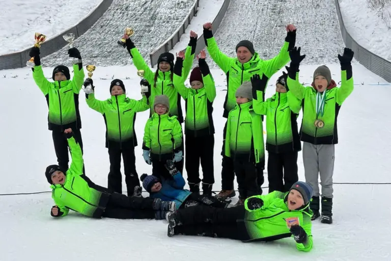 Eine Gruppe von Menschen jubelt vor einer Schisprungschanze.