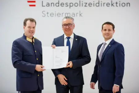 Ein Mann in Polizeiuniform und zwei Männer im Anzug