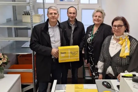 Vier Personen mit einem Paket hinter einem Schreibtisch