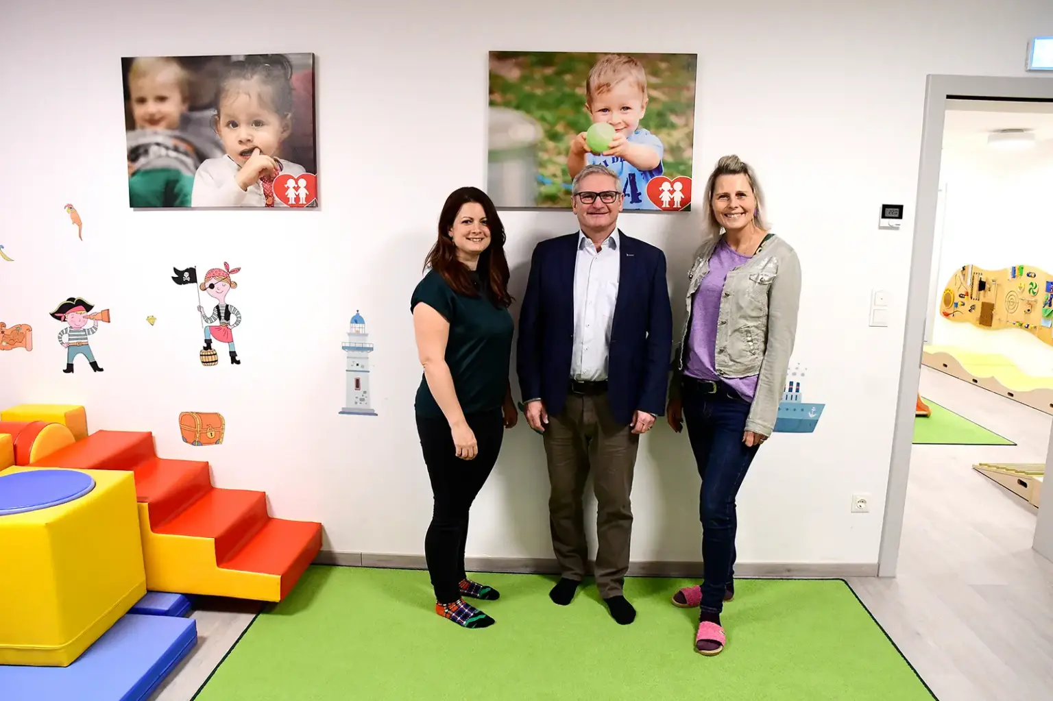 Zwei Frauen und ein Mann in einem für Kinder eingerichteten Spielzimmer