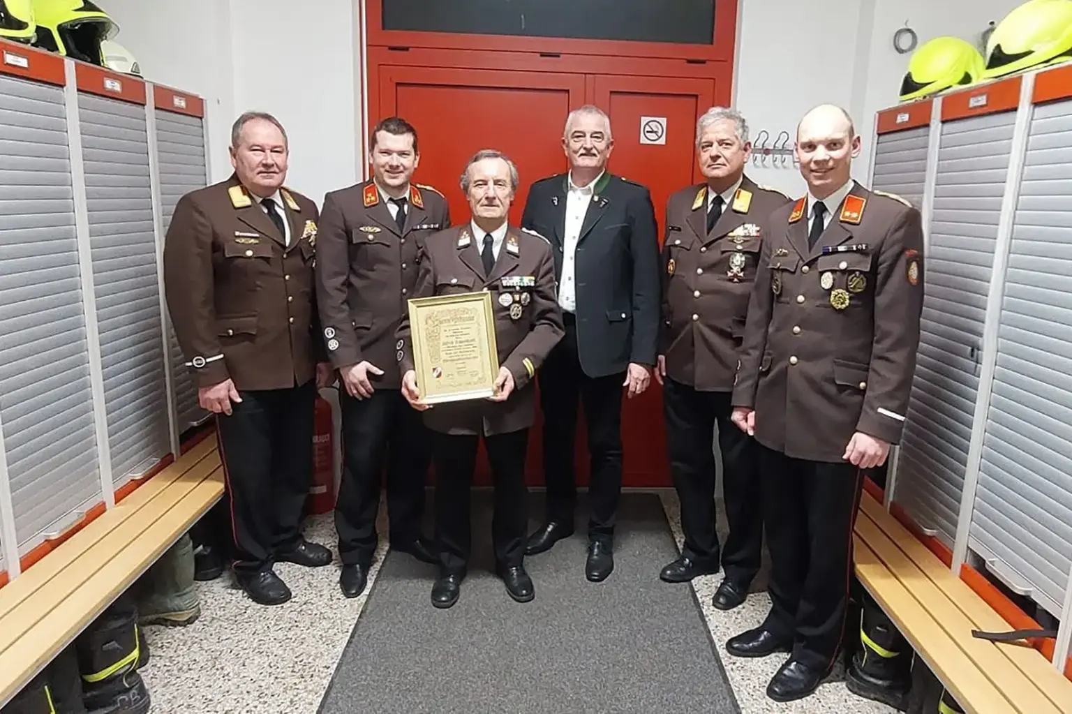 Sechs Männer, zum Teil in Feuerwehruniformen, mit einer Urkunde