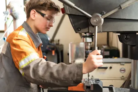 Ein junger Mann bei der großen Bohrmaschine.