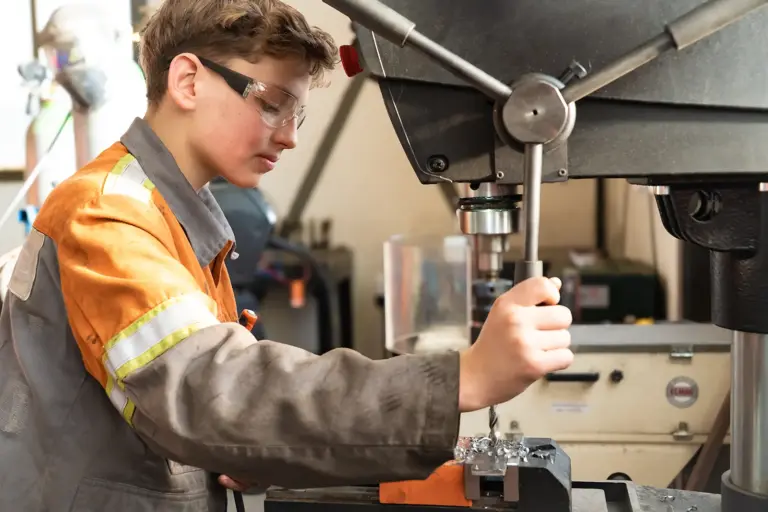 Ein junger Mann bei der großen Bohrmaschine.