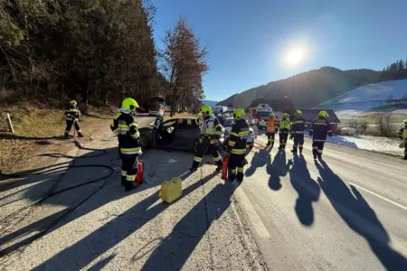 Zwei beschädigte Autos auf einer Straße, Feuerwehrleute sichern die Unfallstelle ab.