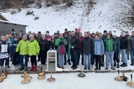 Eine Gruppe von Personen in winterlicher Kleidung auf einer Eisbahn mit Eisstöcken