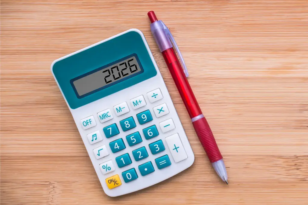 Ein Taschenrechner und eine roter Kugelschreiben auf einem Holz-Untergrund.