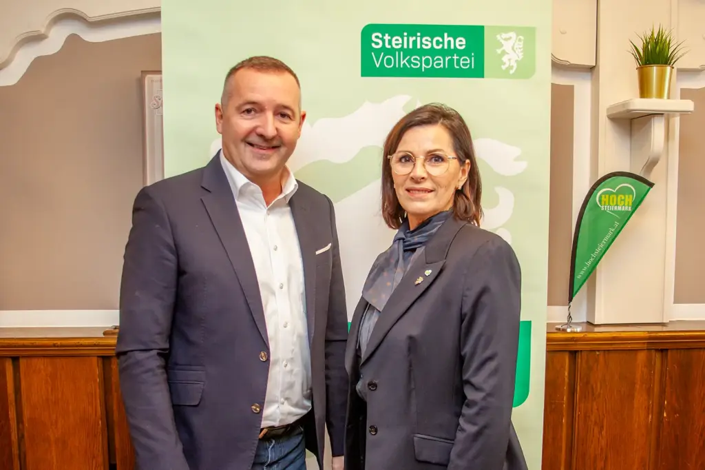 Ein Mann und eine Frau stehen vor einem Werbeaufsteller mit dem Schriftzug Steirische Volkspartei