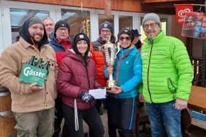 Neue Eisstockmeister gekürt Sieben Personen in Winterkleidung präsenteren einen Pokal und weitere Preise