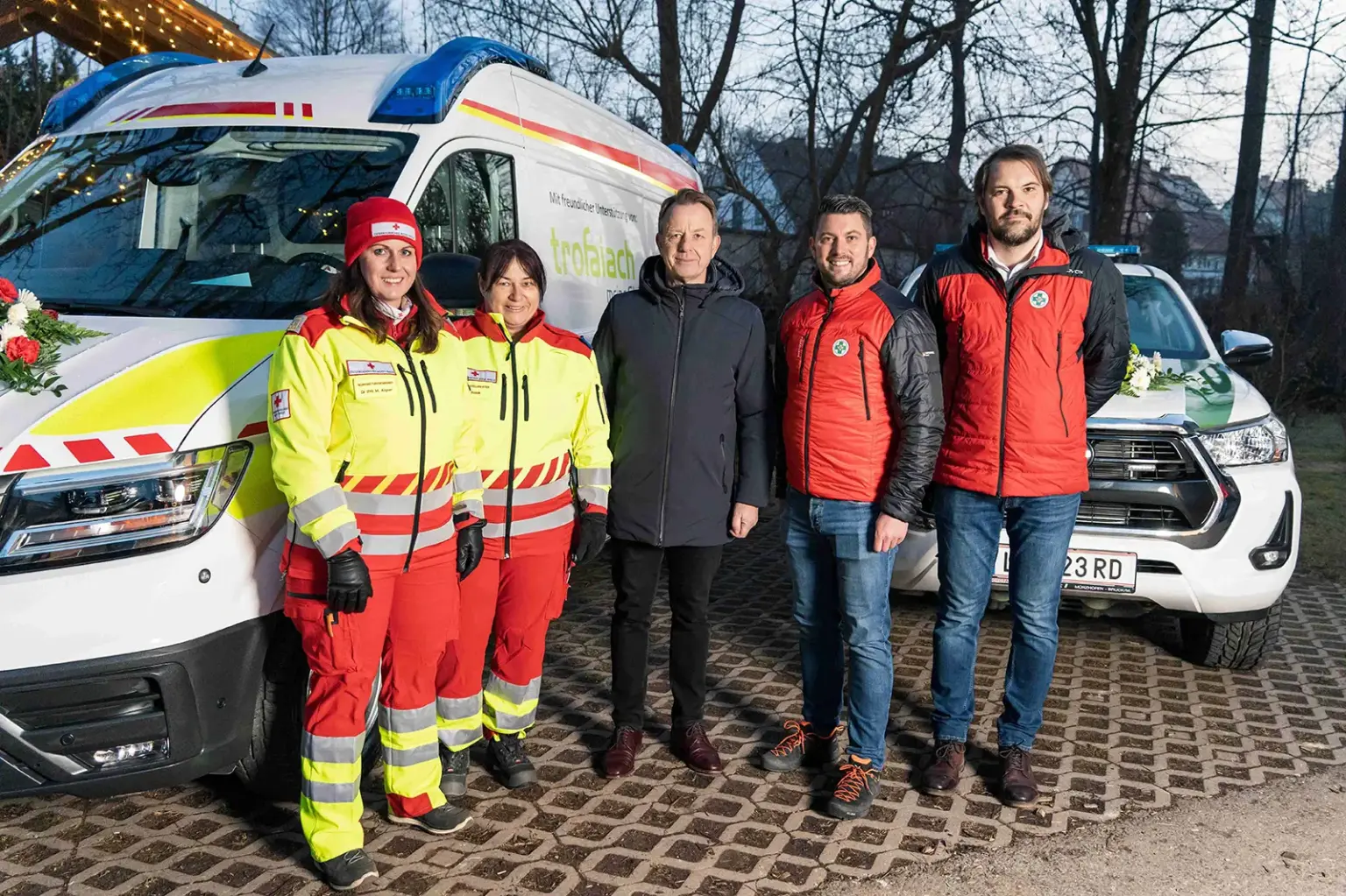 Fünf Personen vor zwei Einsatzfahrzeugen
