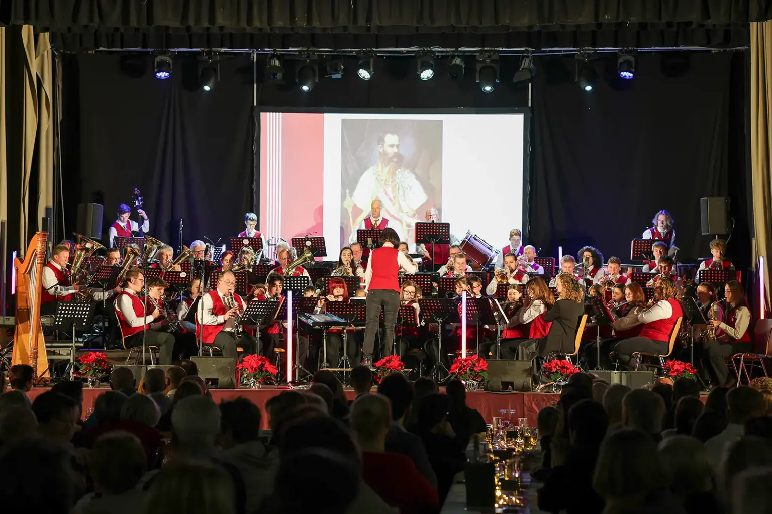 Eine Musikkapelle spielt auf einer Bühne vor zahlreichem Publikum