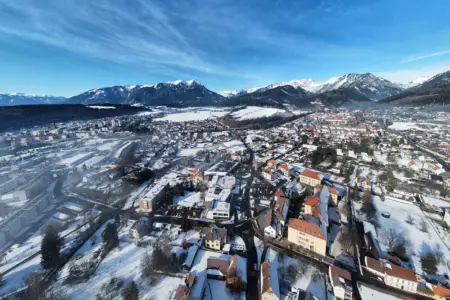 Eine Luftaufnahme einer winterlichen Stadt mit Bergen im Hintergrund