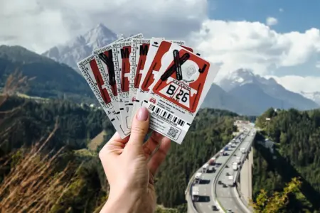 Die letzte Klebevignette ist „feuerrot“ Eine Hand hält mehrere Vignetten, im Hintergrund ist eine Landschaft mit einer Autobahn zu sehen